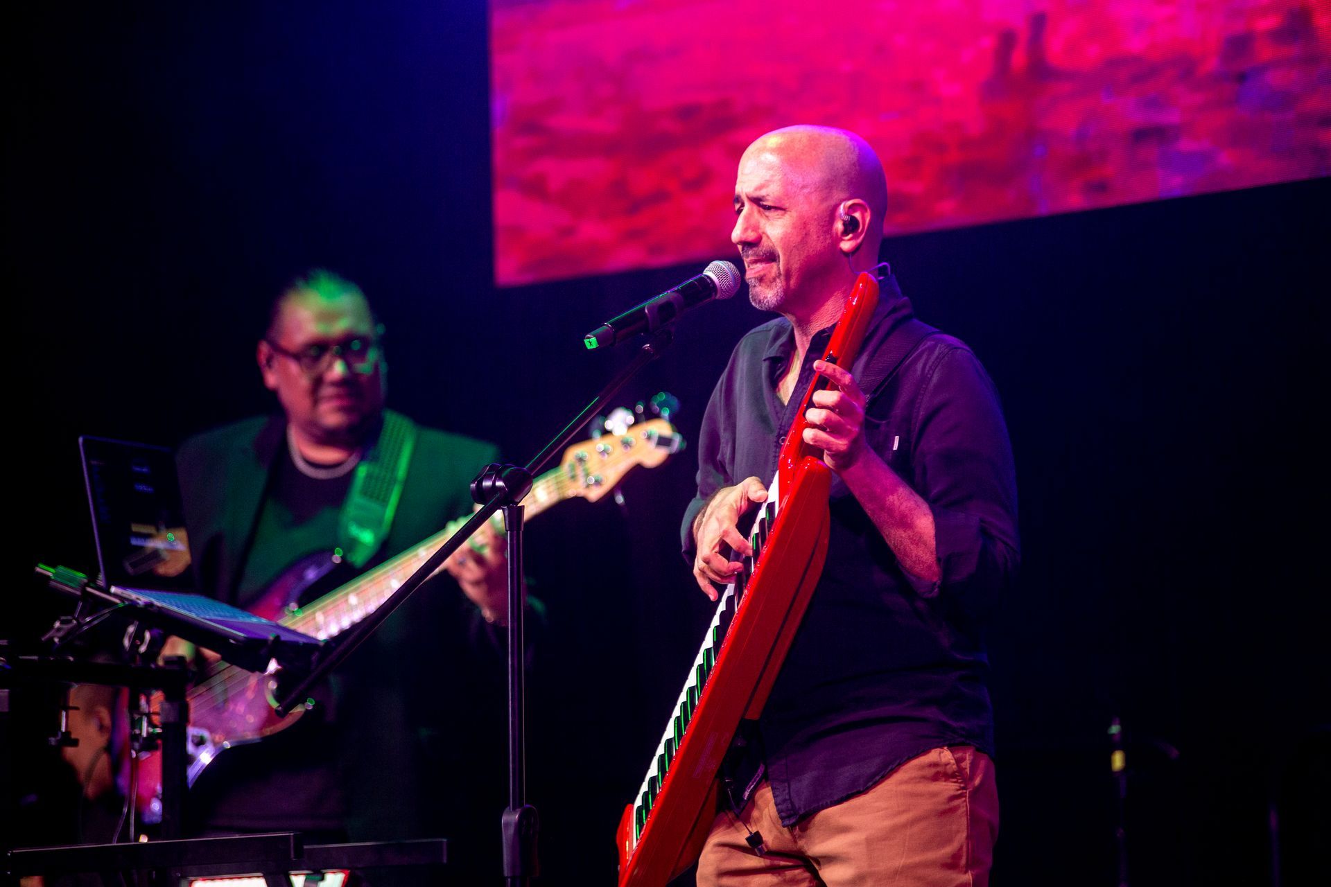 Un hombre toca una guitarra y canta en un micrófono en un escenario.