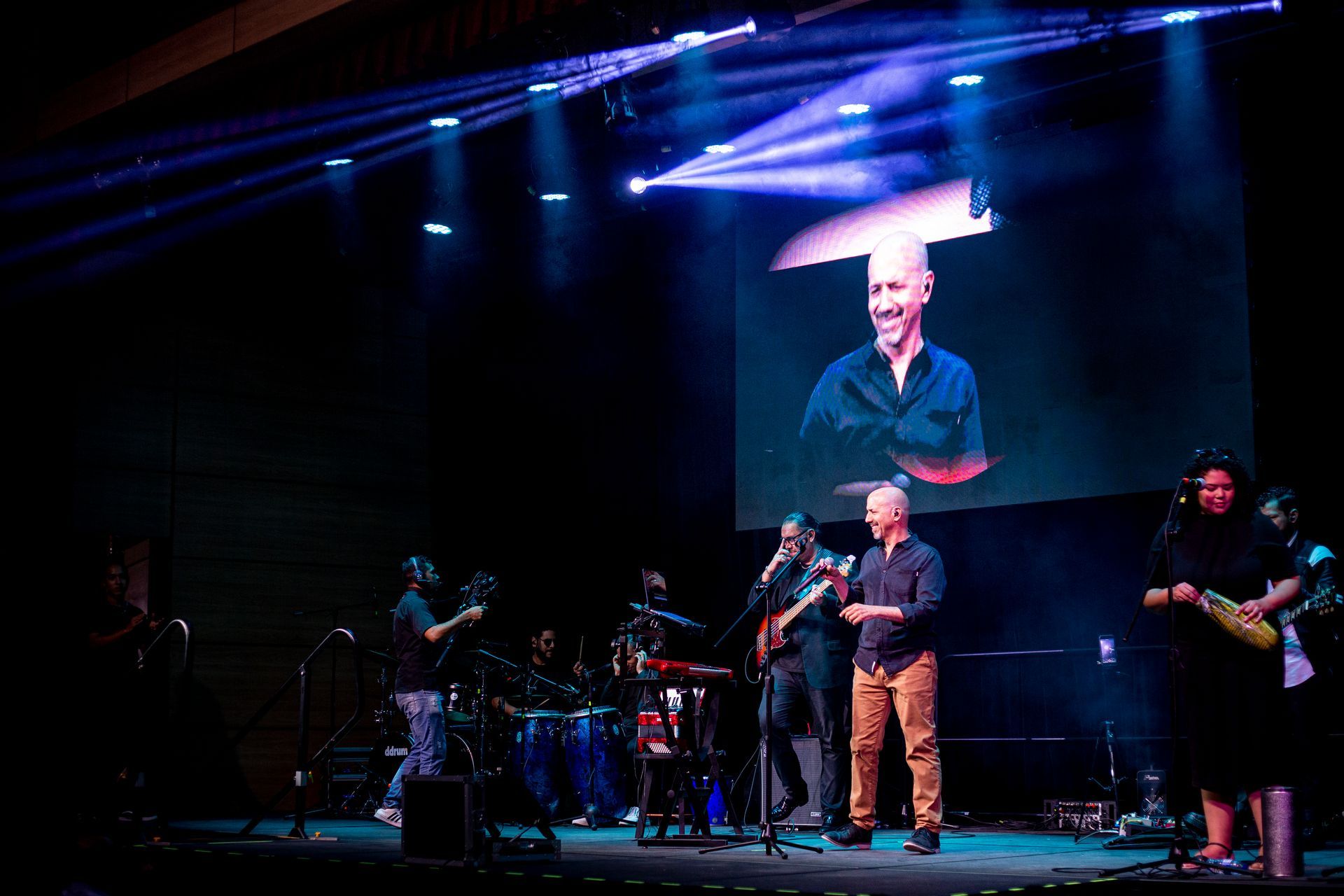 Un grupo de personas está de pie en un escenario frente a una pantalla grande.