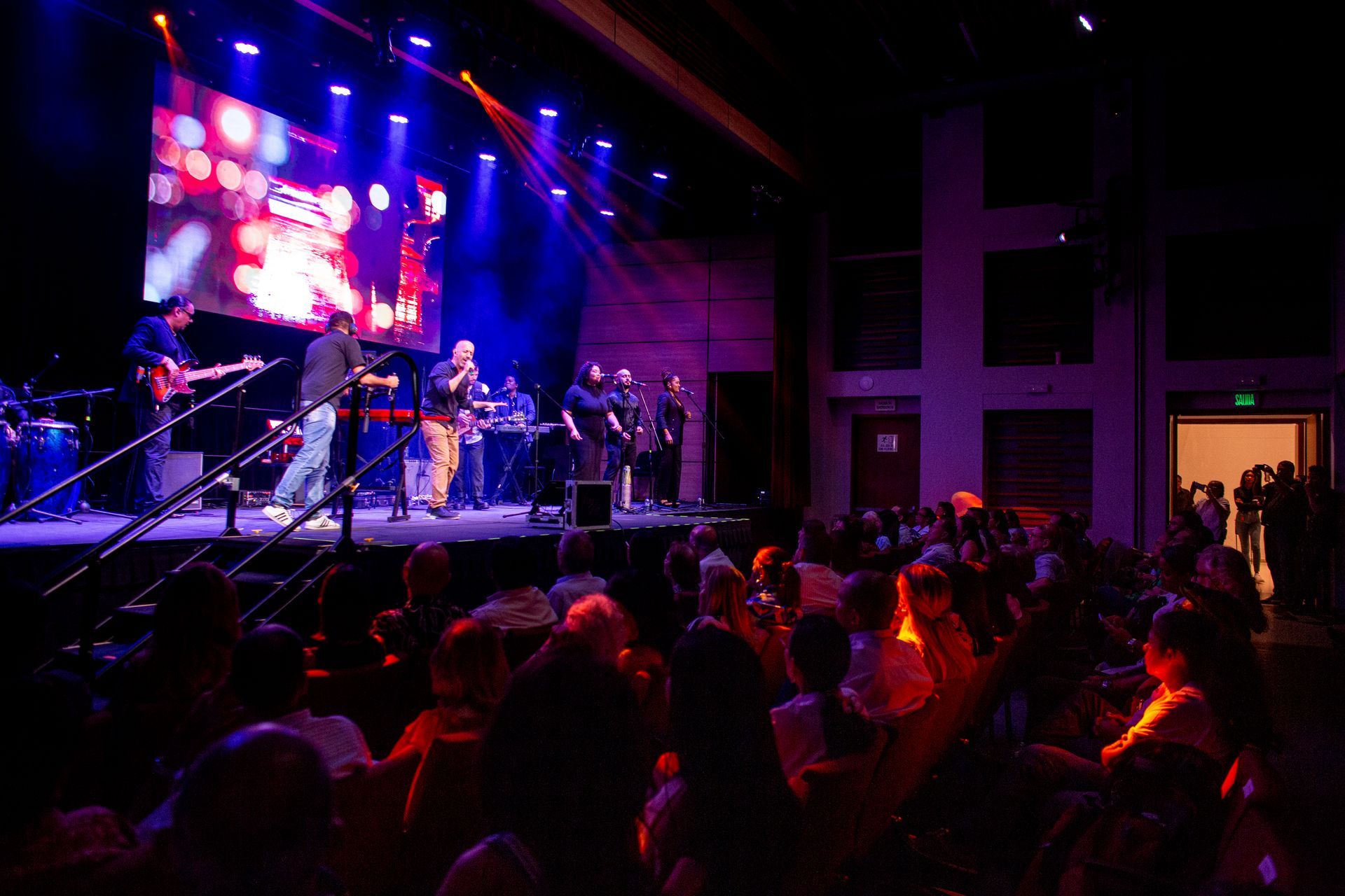 Un grupo de personas está sentada frente a un escenario en un concierto.