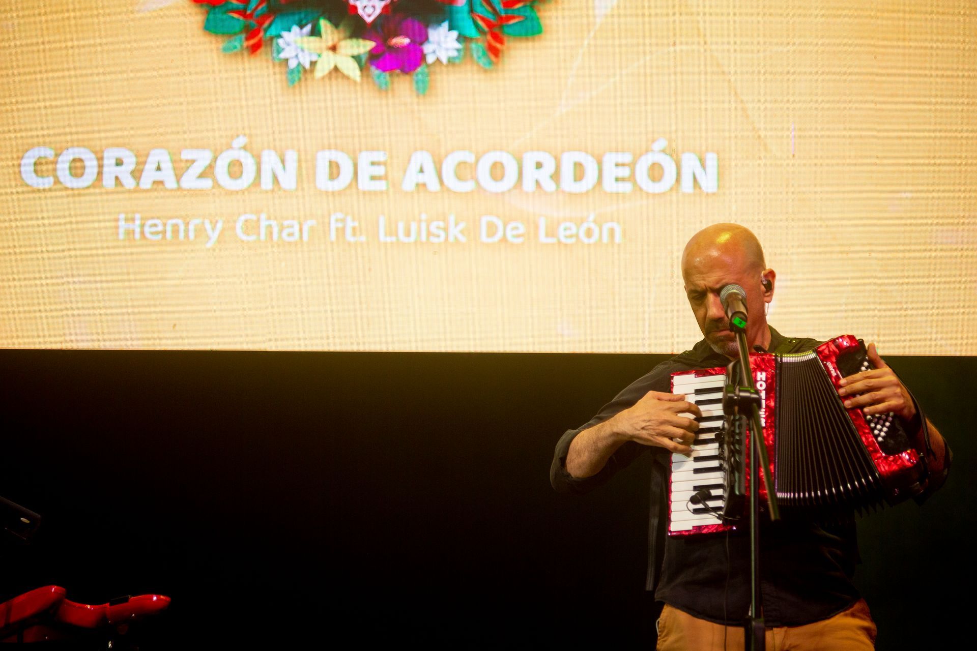 Un hombre está tocando un acordeón en un escenario frente a un micrófono.