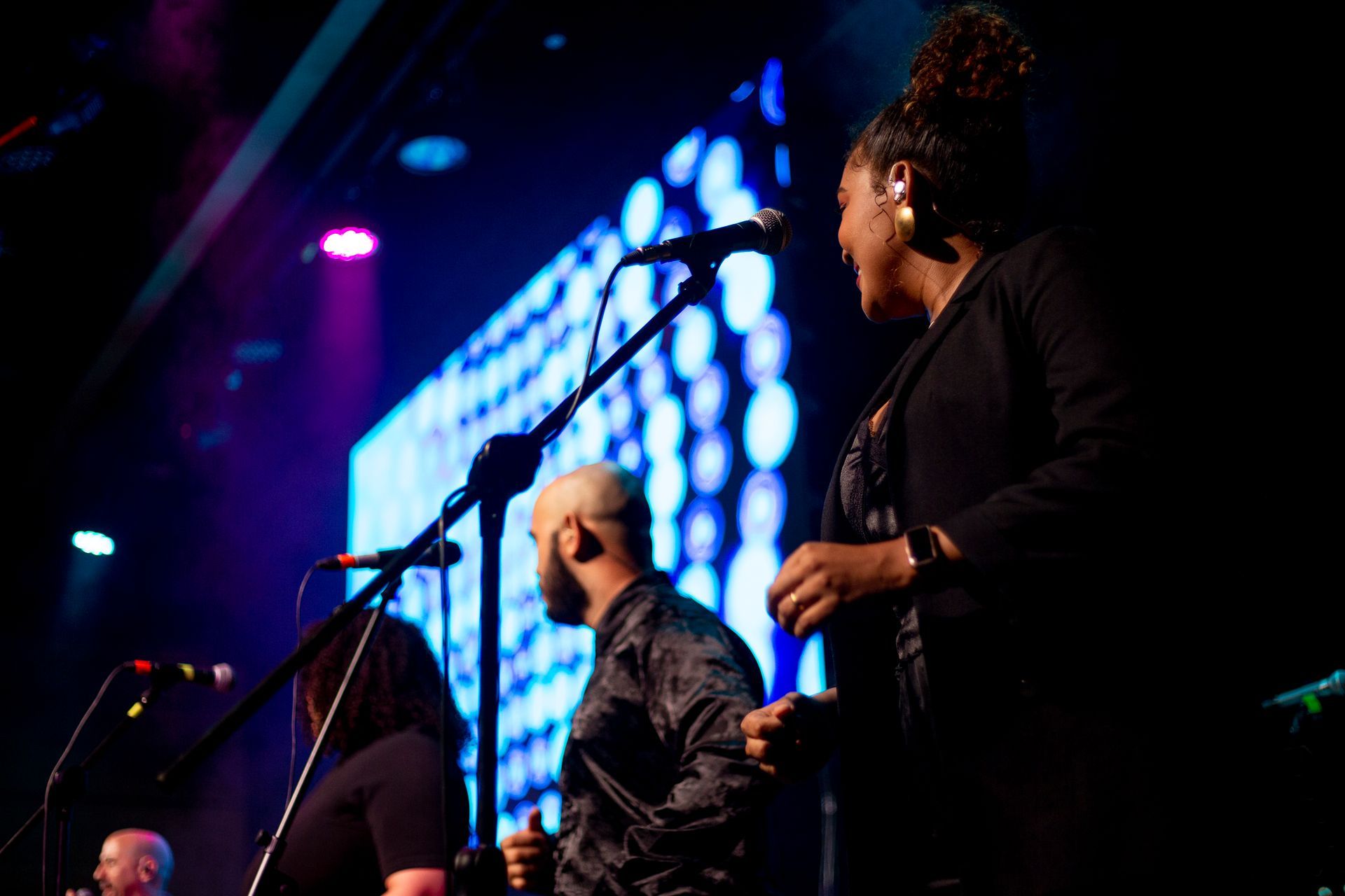 Un hombre y una mujer están cantando frente a micrófonos en un escenario.