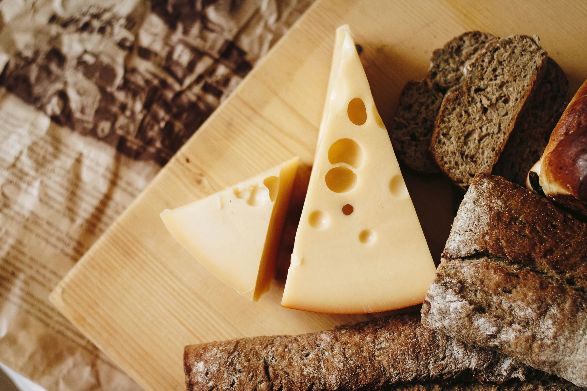 Cheese and bread on a wooden board, with paper in the background.