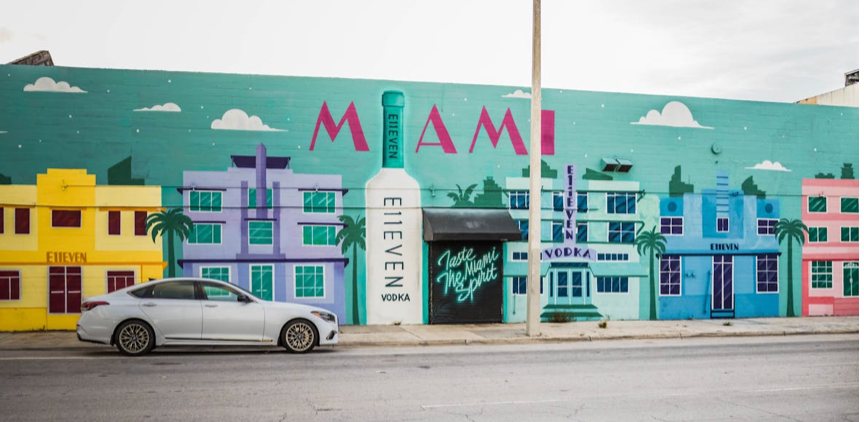 A car is parked in front of a miami mural