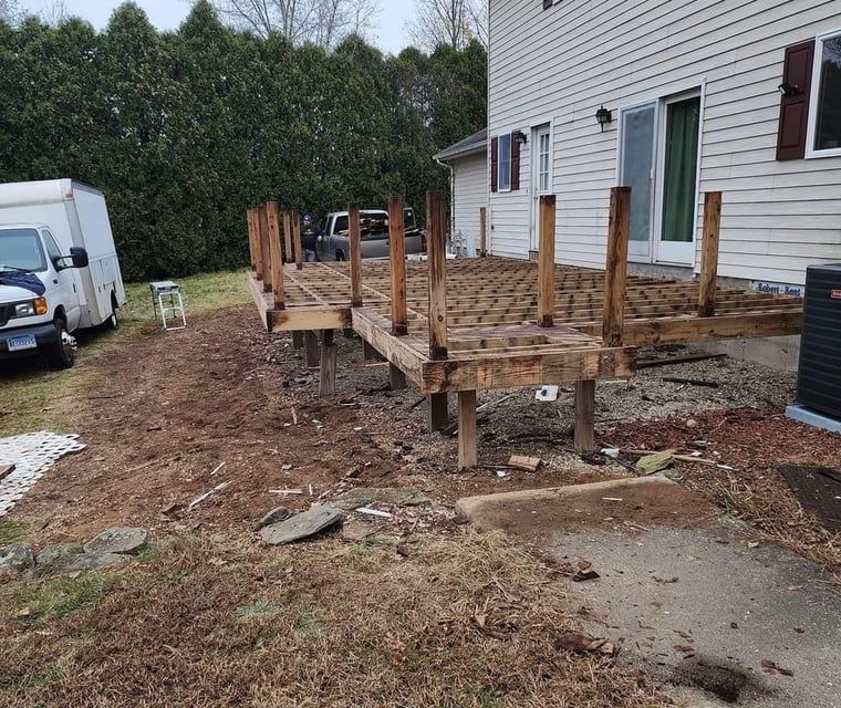 A wooden deck is being built in front of a house.