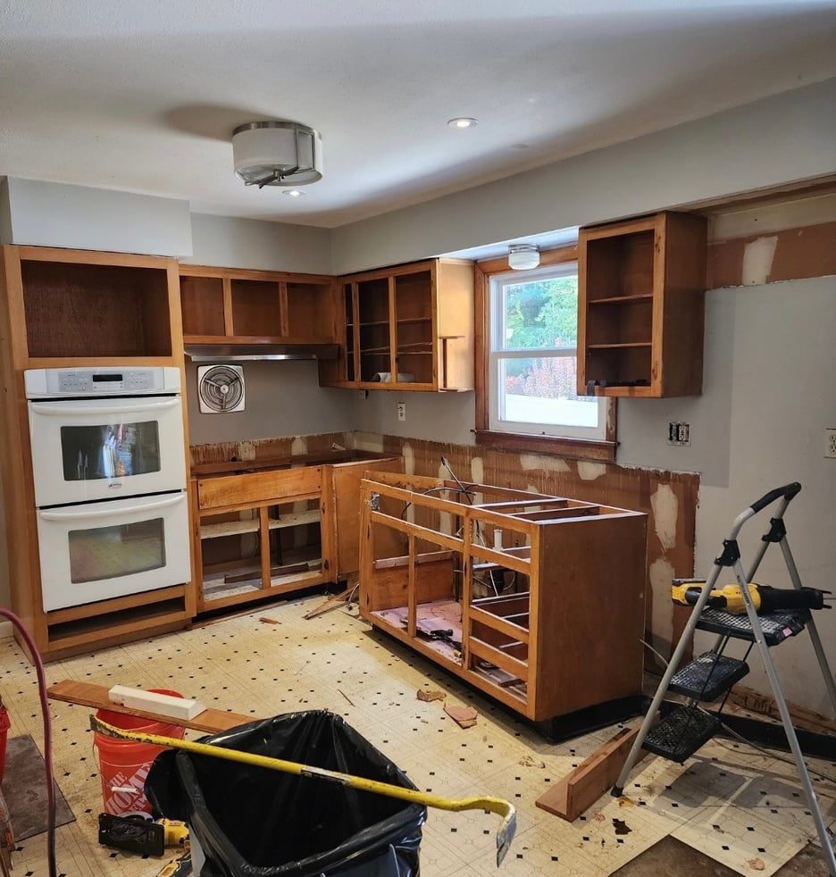 A kitchen under construction with a ladder and a measuring tape