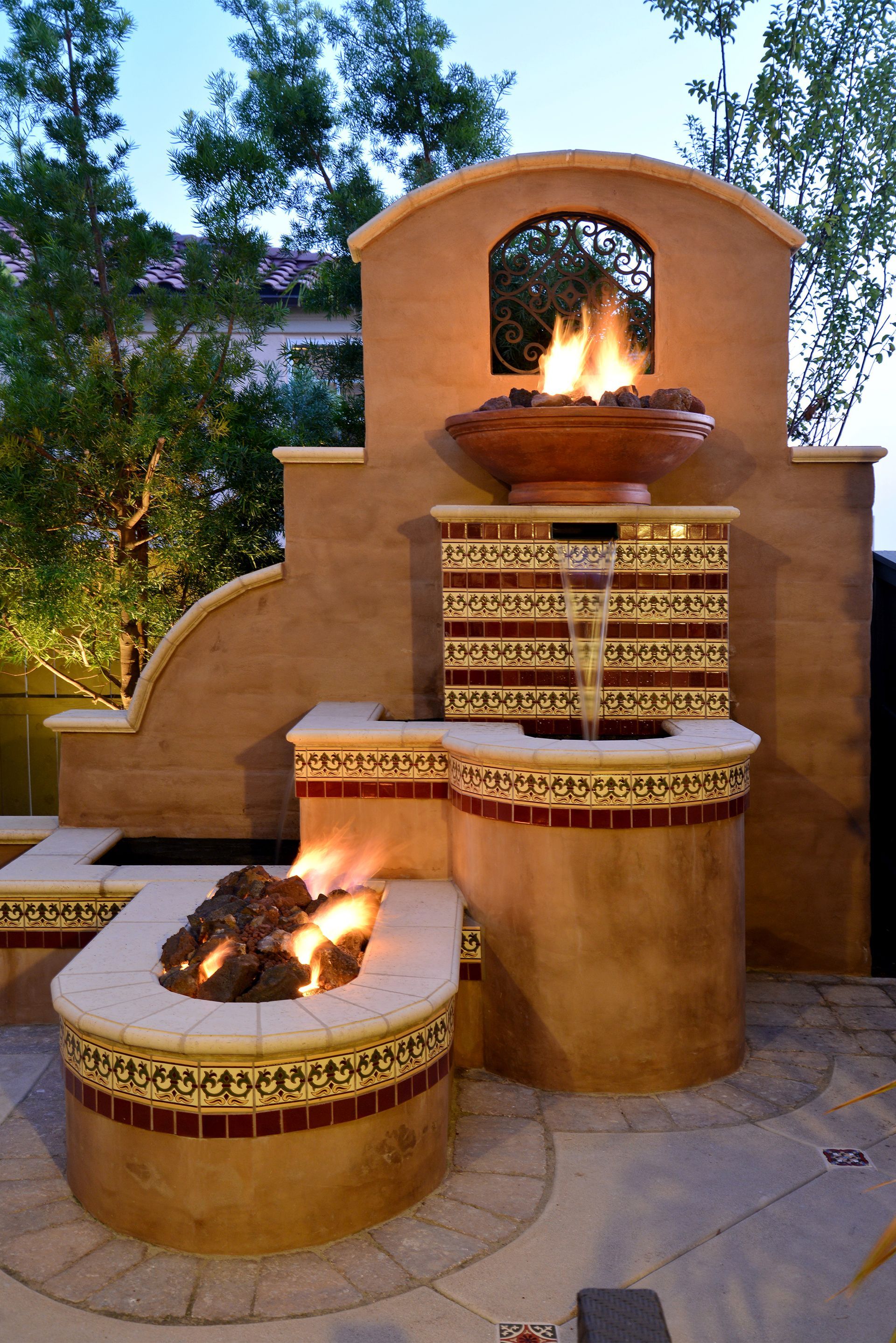 A fire pit with a fountain in the background