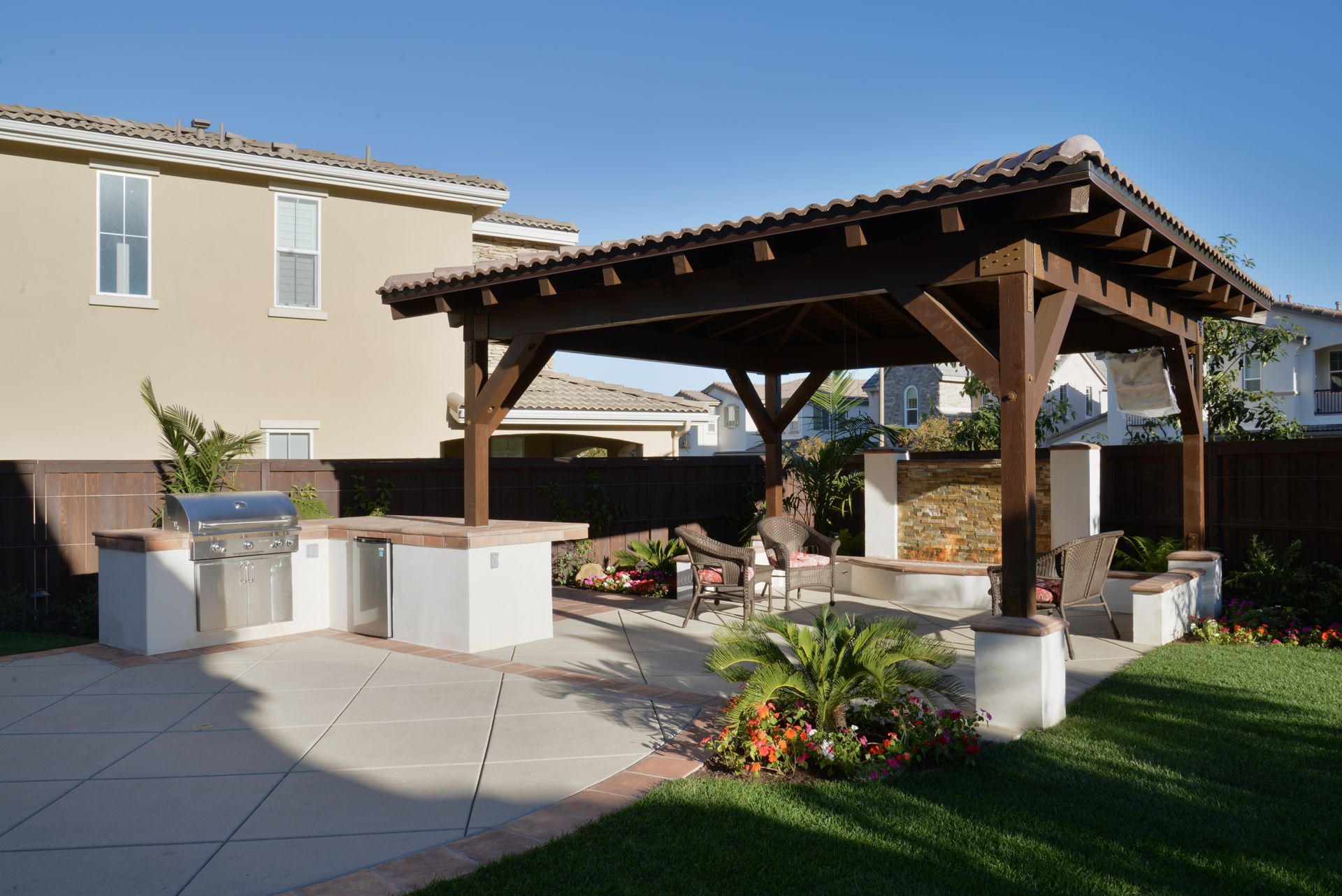 A backyard with a wooden gazebo and a grill