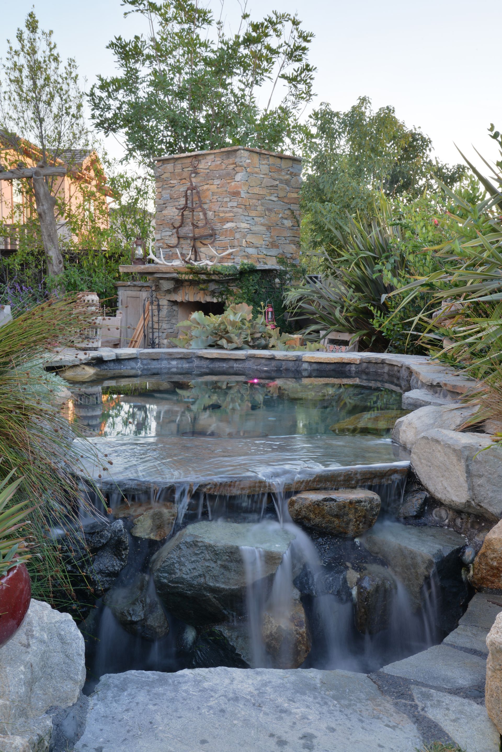 A waterfall is surrounded by rocks and trees in a garden.