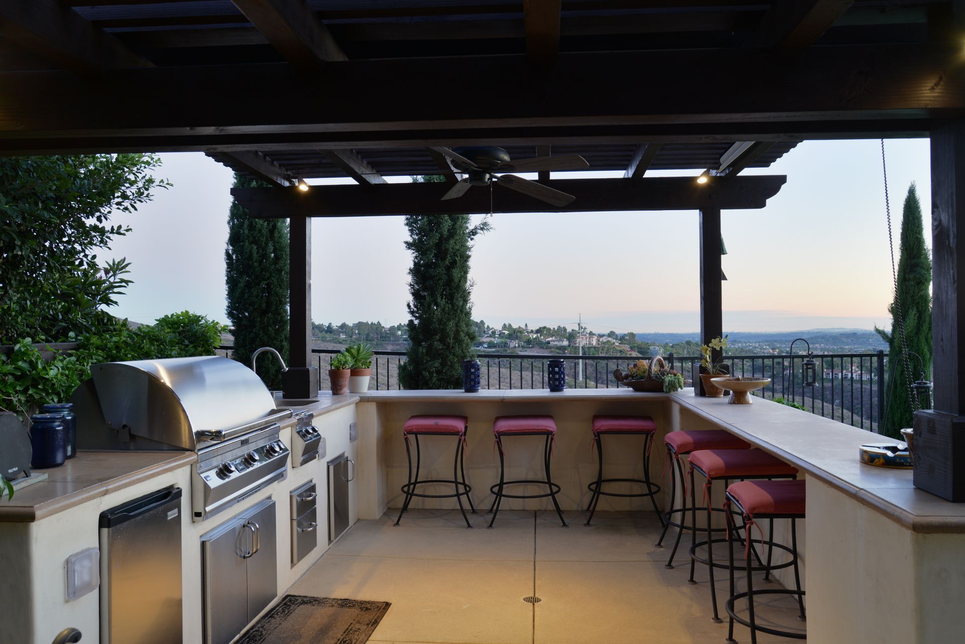 A large outdoor kitchen with a grill and stools