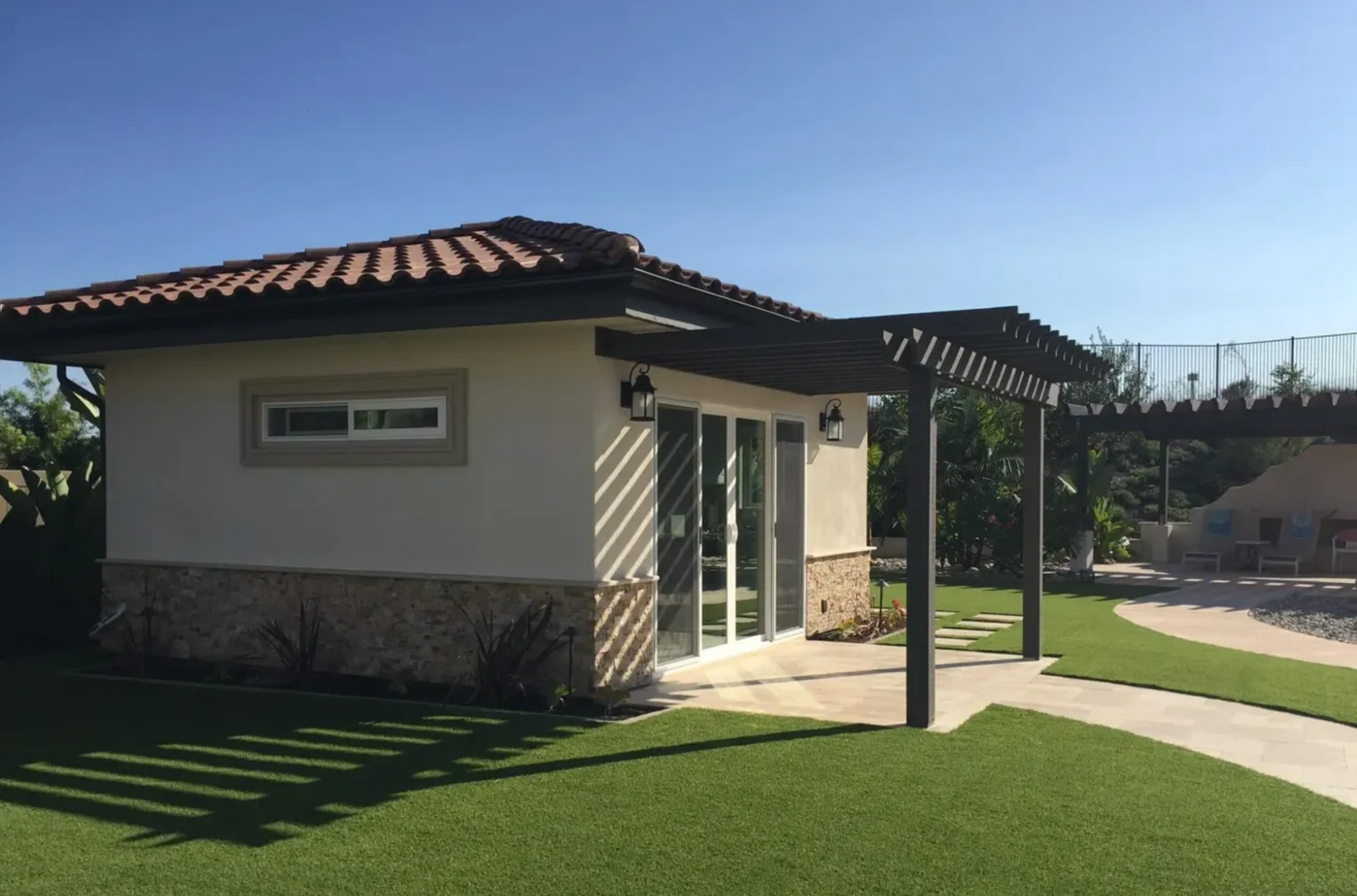 A small house with a pergola on the side of it