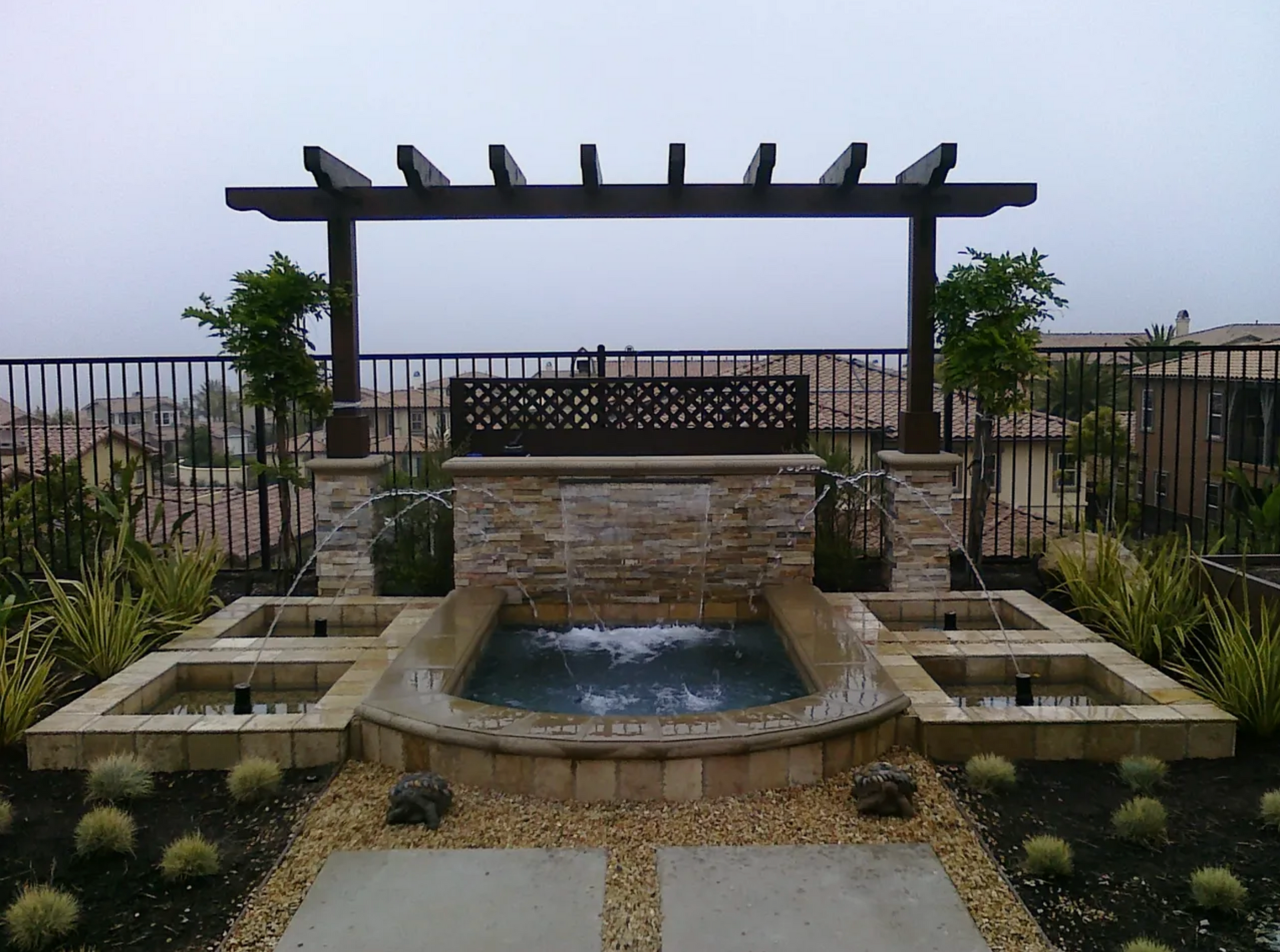 A patio with a pergola and a water feature