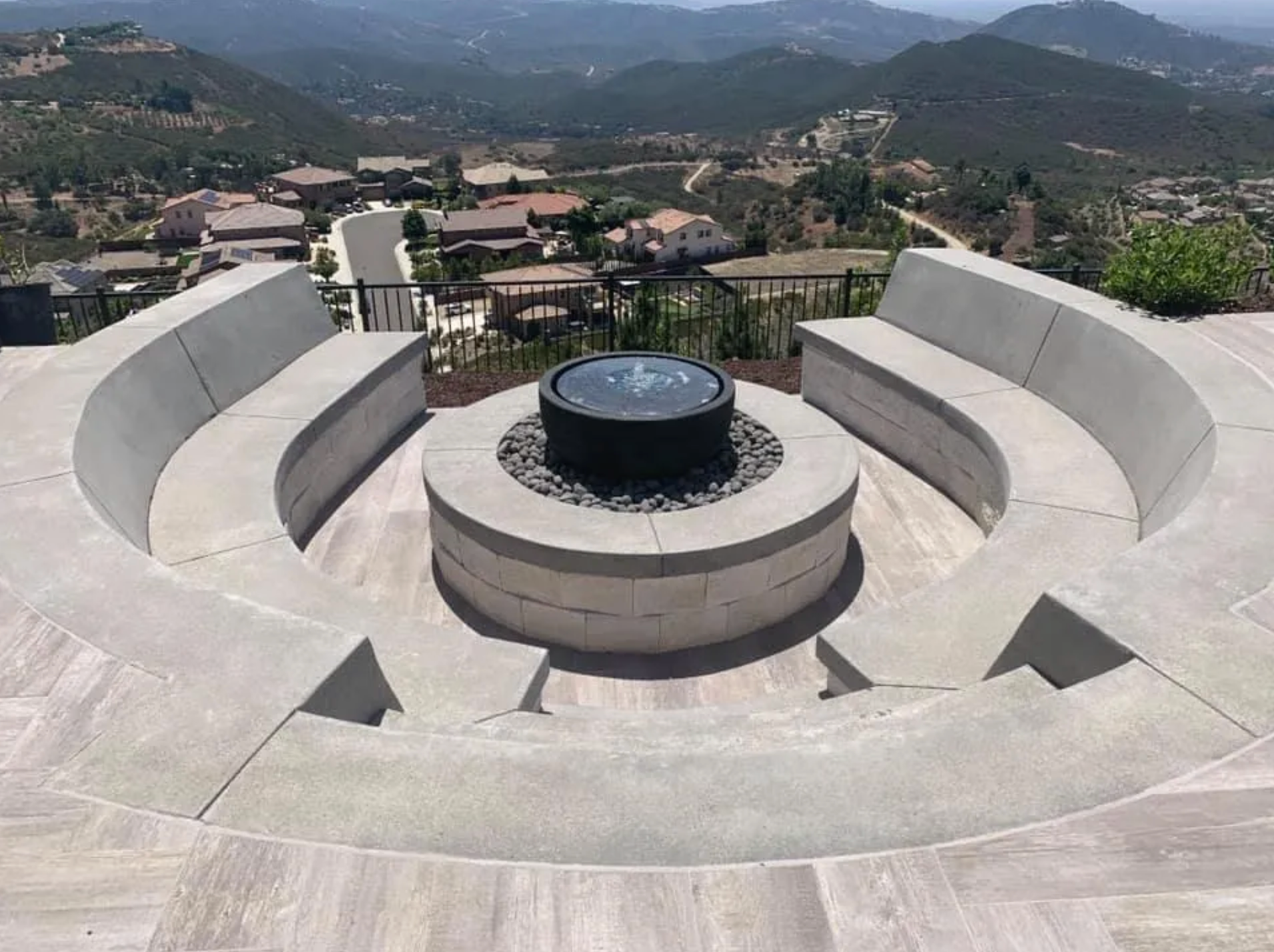 There is a fire pit in the middle of the patio with a view of the mountains.