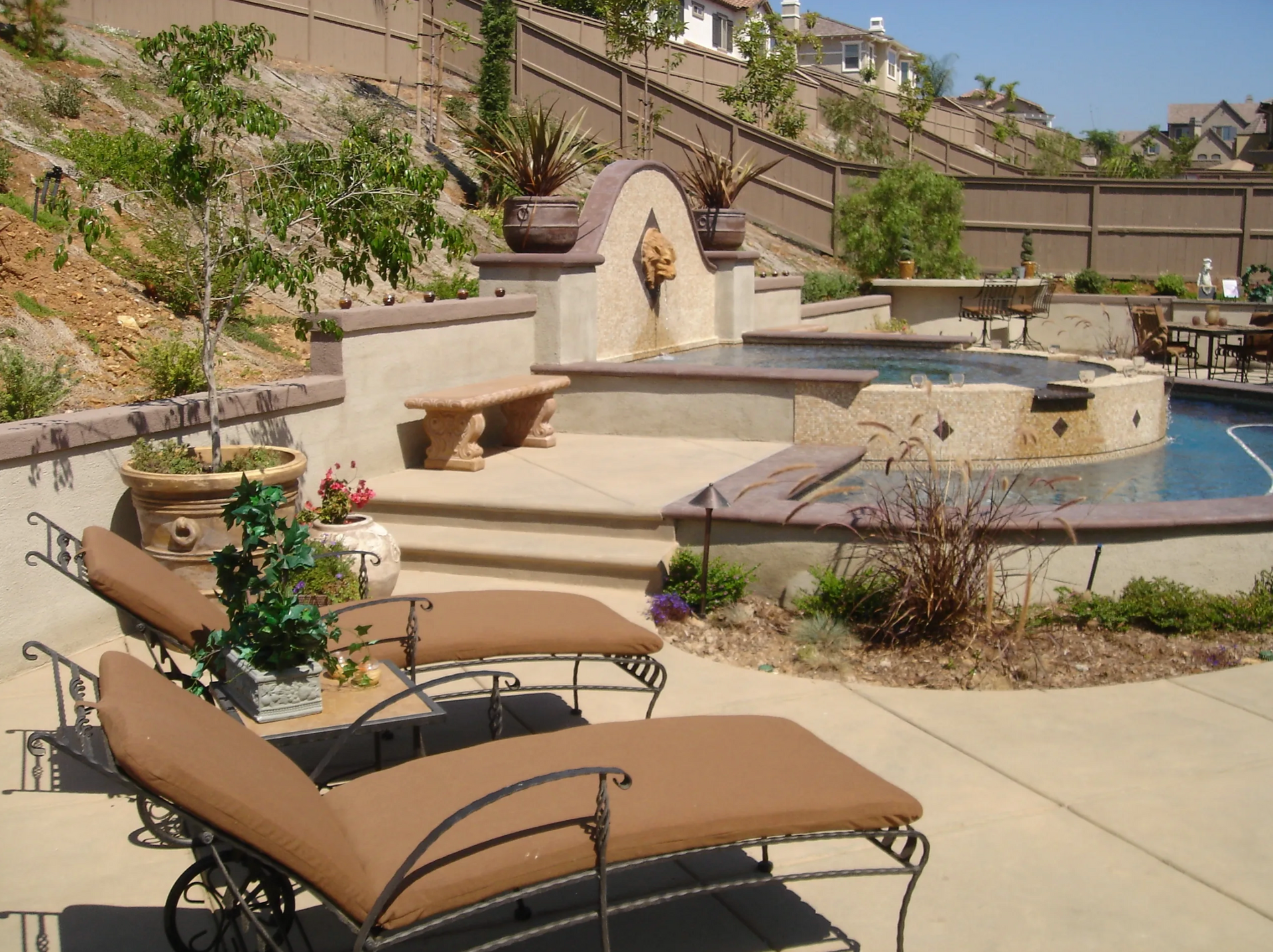 A patio with lounge chairs and a pool in the background