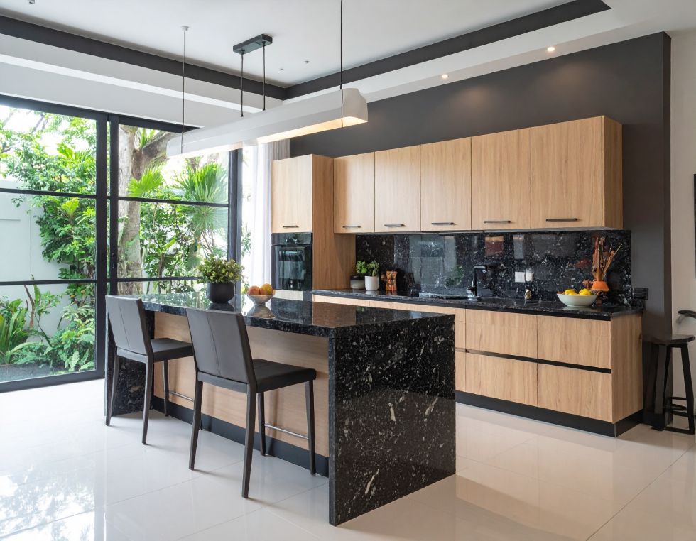 Modern kitchen with a black granite island and countertops, light wood cabinets, and large window overlooking a garden.
