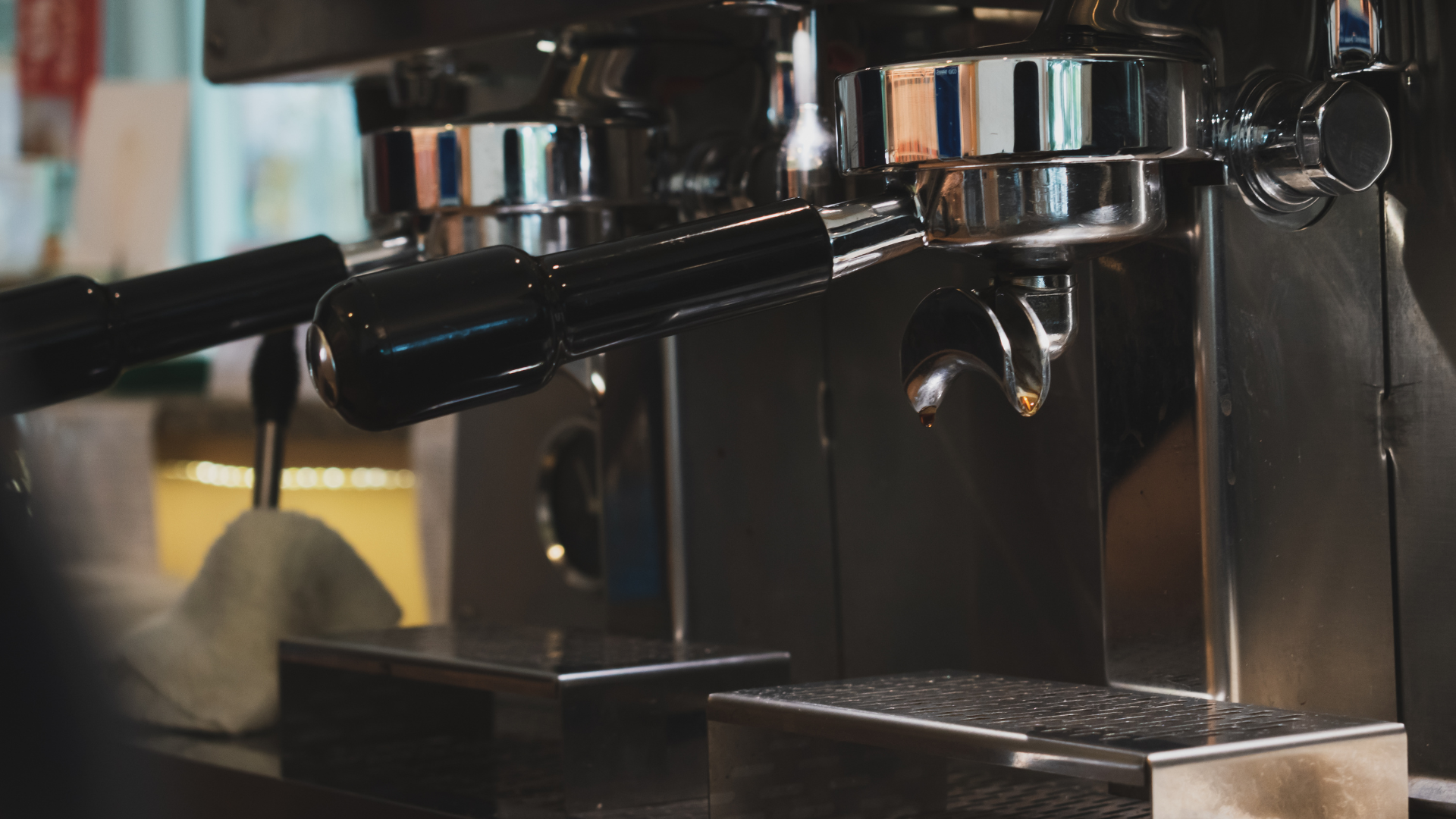 A close-up view of the chrome portafilter heads and handles of a professional espresso machine.