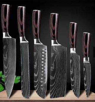 A set of six kitchen knives with dark wood handles and patterned Damascus steel blades lined up on a wooden surface.