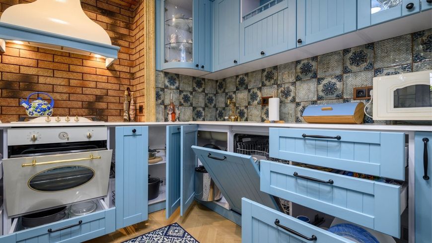 Modern blue kitchen with open cabinets, patterned backsplash, and a white stove under a lit hood
