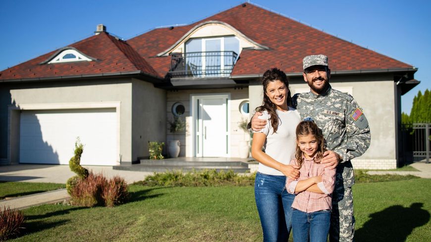 Family standing in front of a suburban house with a red roof and garage, smiling in the front yard