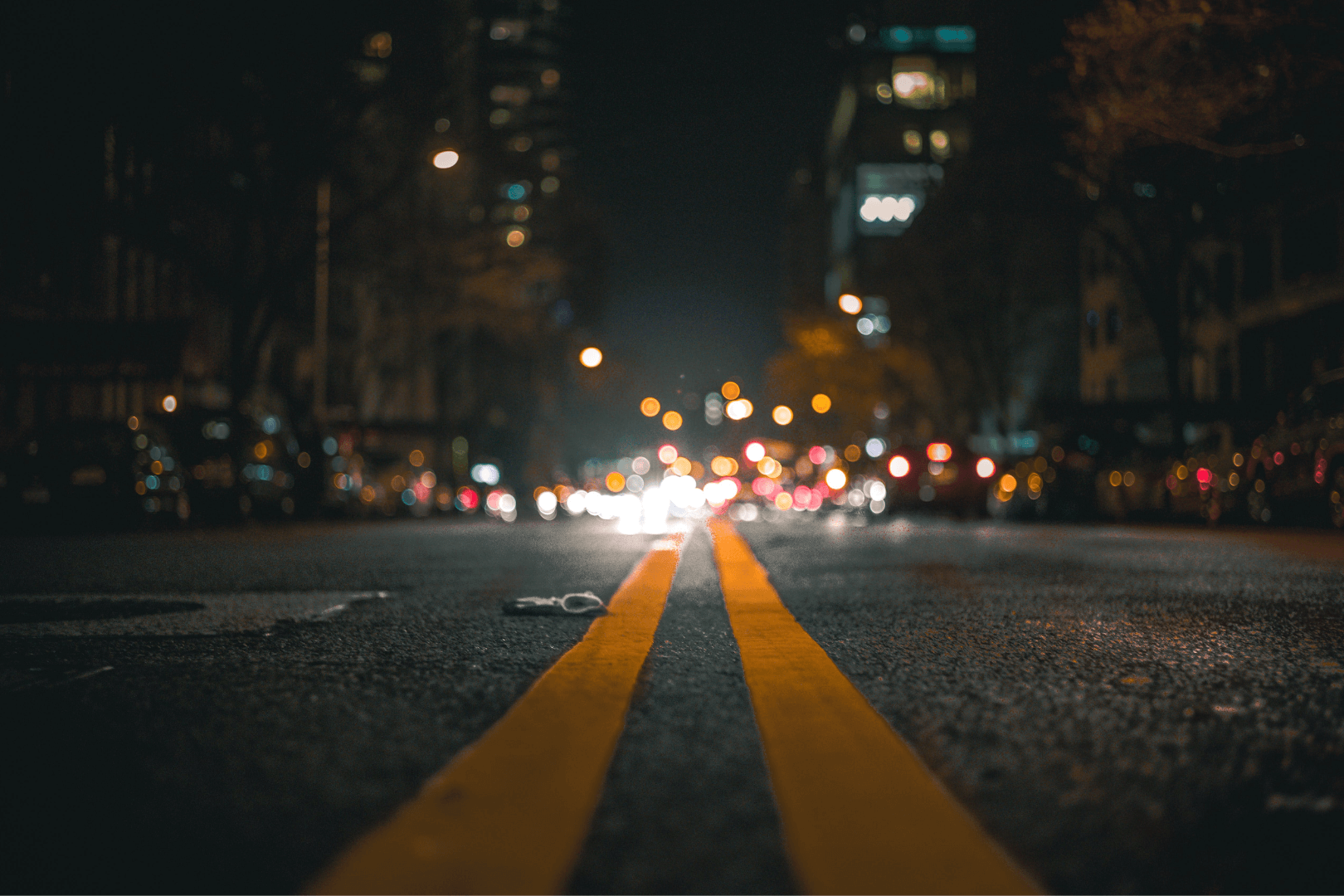 A dark blue house with a white garage door and a long concrete driveway against a clear blue sky.