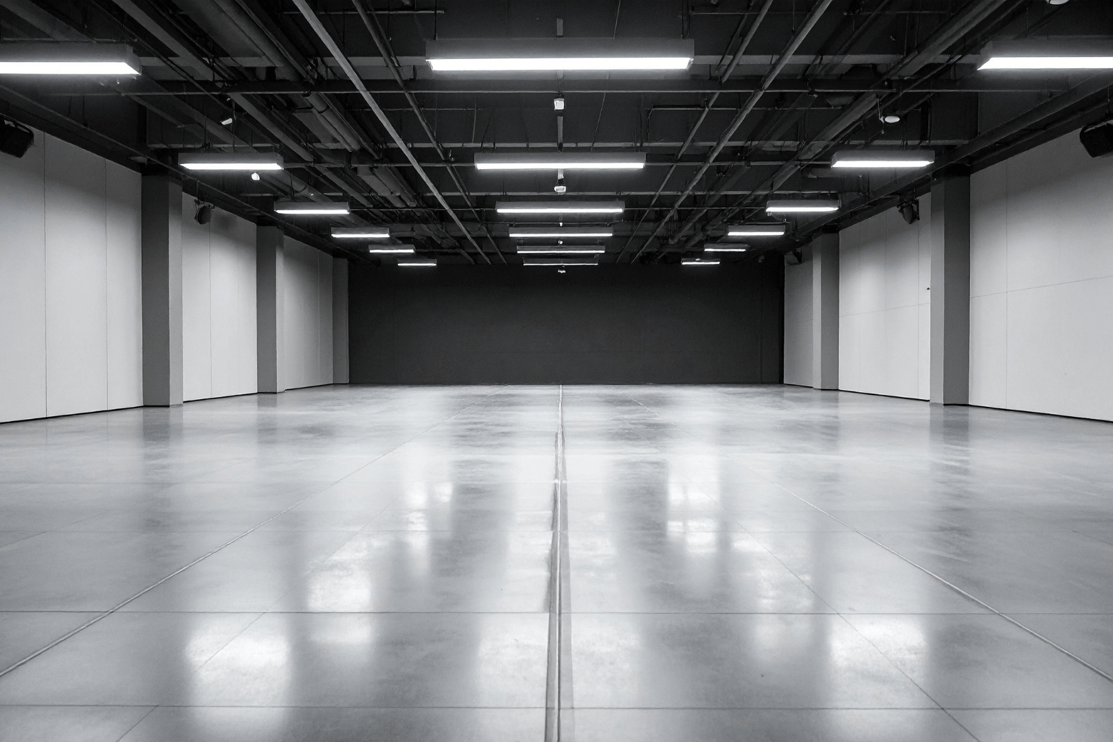 A dark blue house with a white garage door and a long concrete driveway against a clear blue sky.