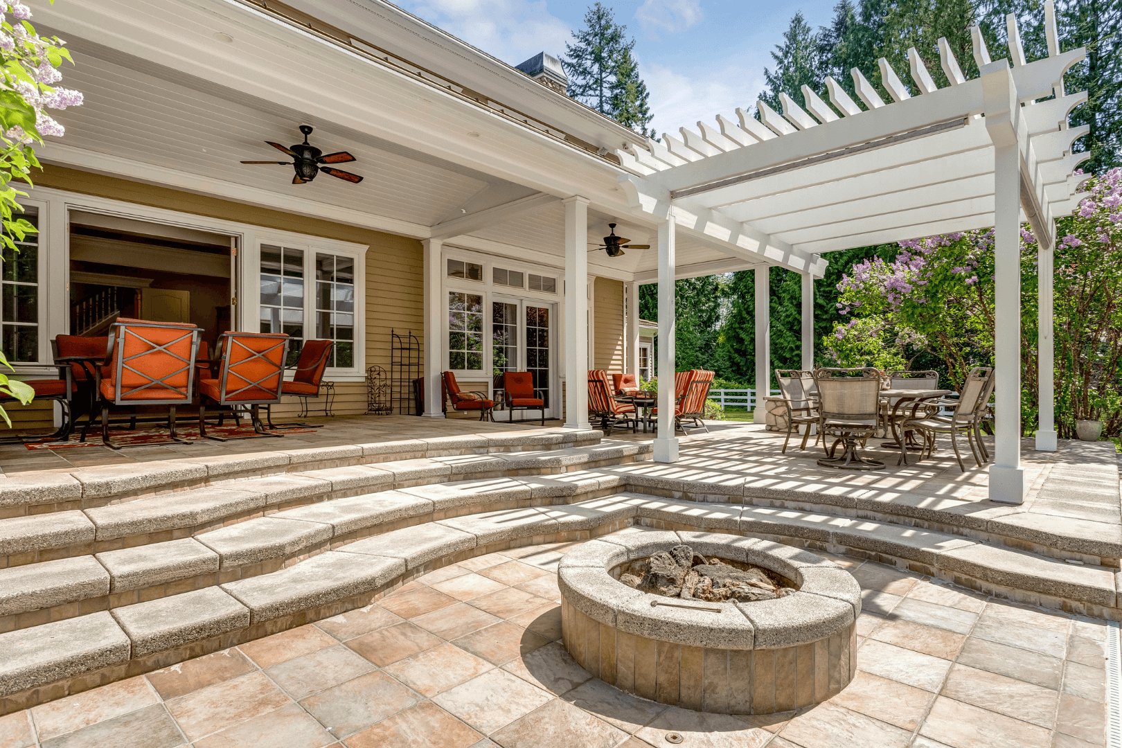 A dark blue house with a white garage door and a long concrete driveway against a clear blue sky.