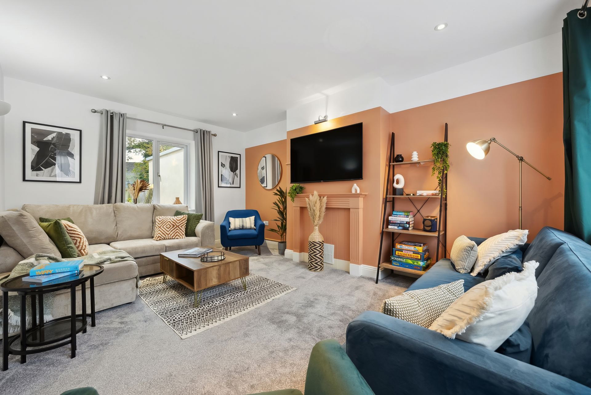 Living room with light-colored carpet, two sofas, a coffee table, and a wall-mounted TV. One wall is painted coral.