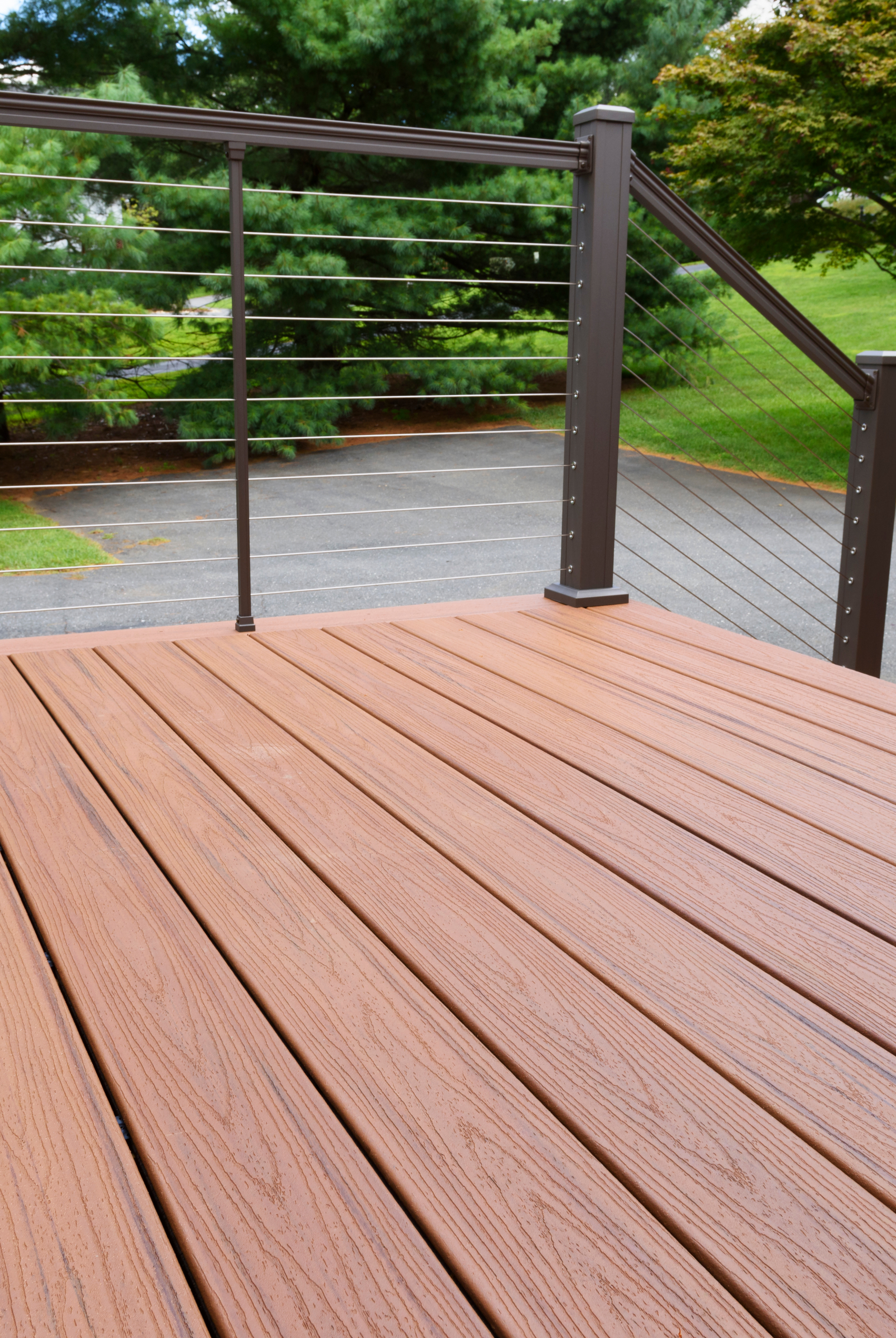 A wooden deck with a metal railing and trees in the background Jarvis & Son Renovations,