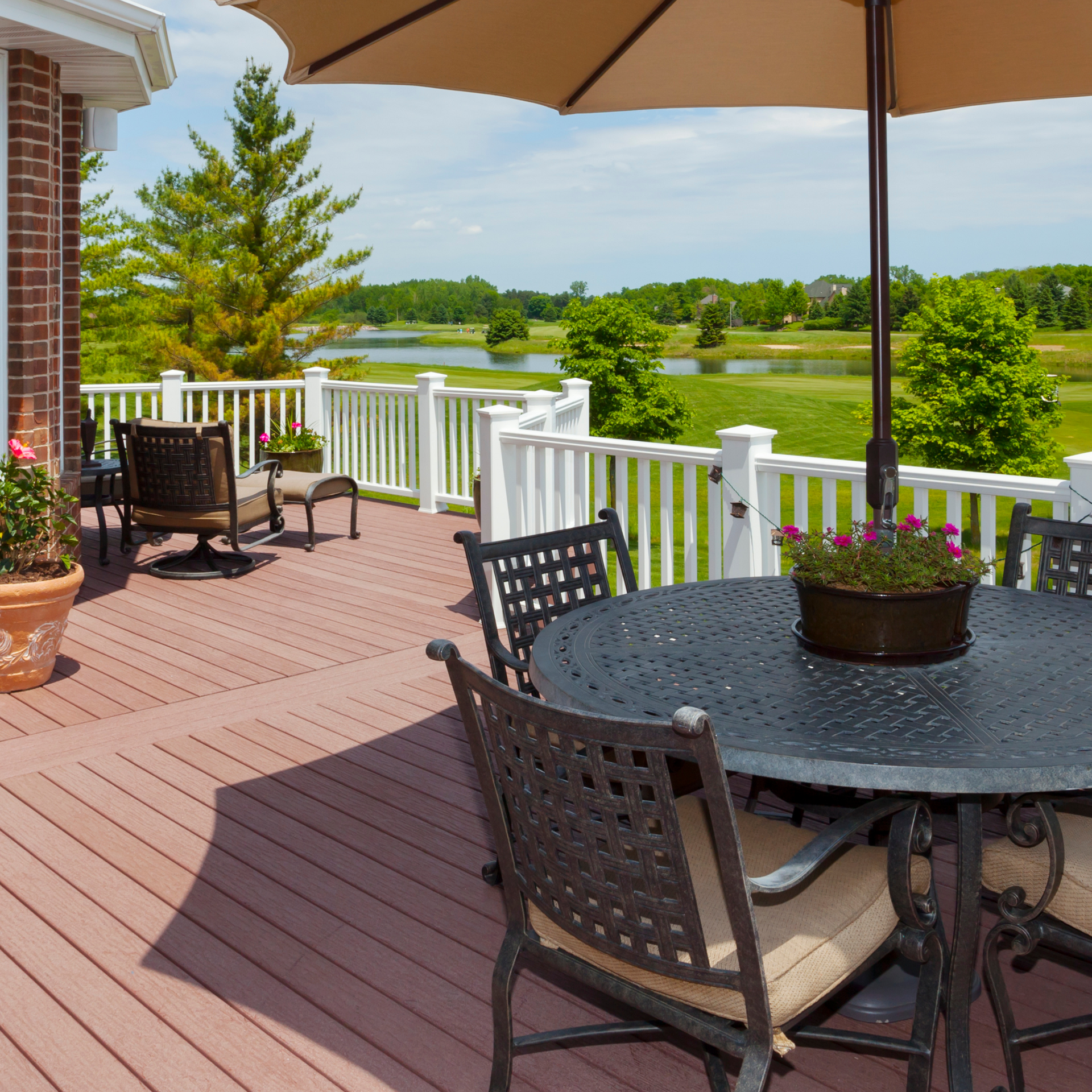 A table and chairs on a deck with an umbrella Jarvis & Son Renovations,