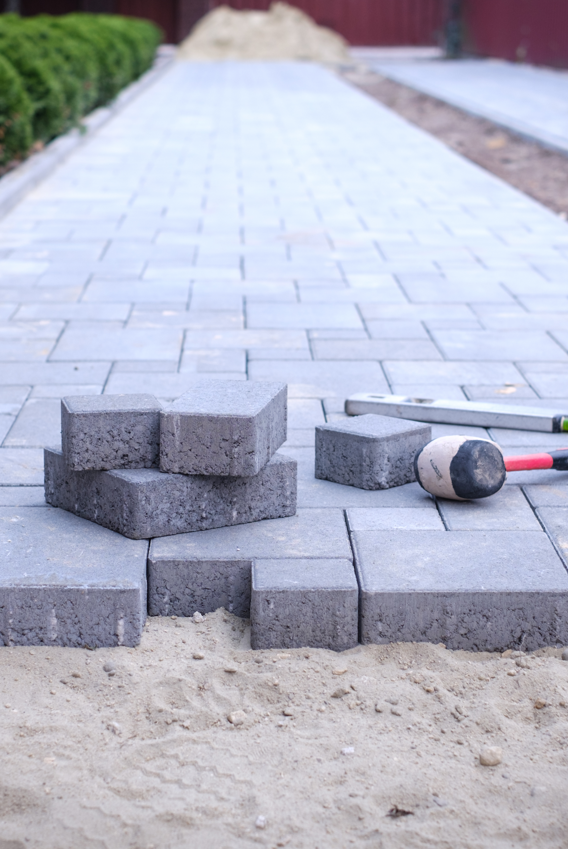 A concrete walkway is being built with bricks and a hammer. Jarvis & Son Renovations,