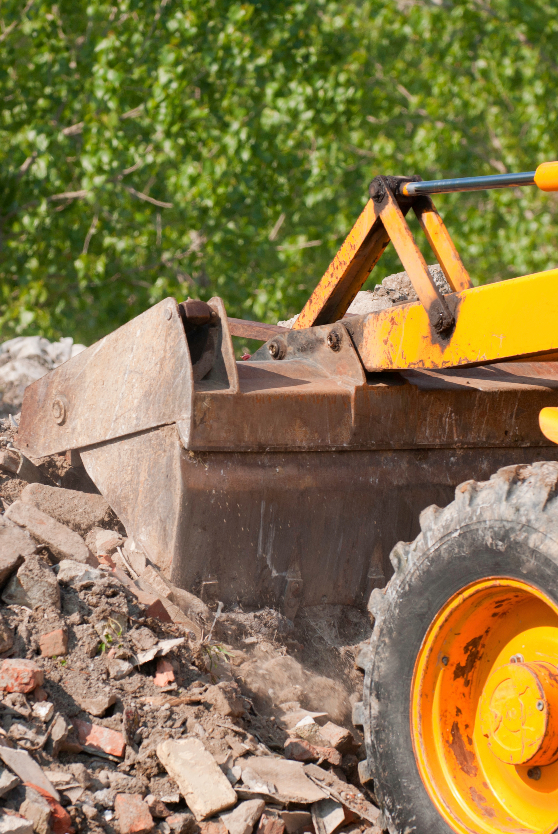 A yellow bulldozer is clearing dirt and rocks on a construction site. Jarvis & Son Renovations,