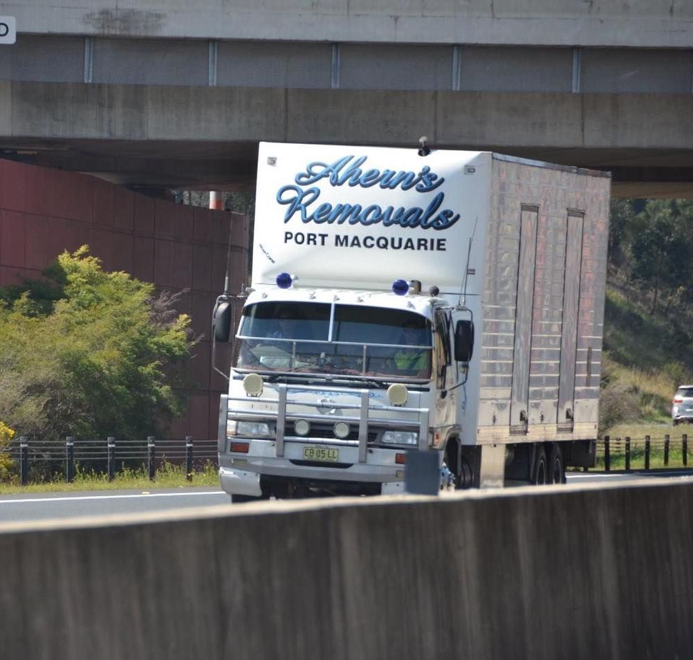 A Removals Truck Drives Down A Highway Under A Bridge — Ahern's Removals In Wauchope, NSW