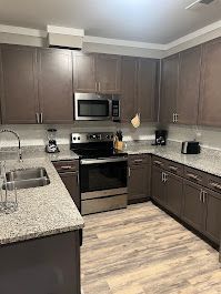 Brown kitchen with stainless steel appliances, granite countertops, and light wood flooring.