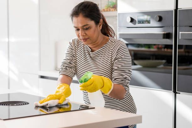Home deep cleaning of a kitchen by a woman, ensuring a spotless and healthy living space.