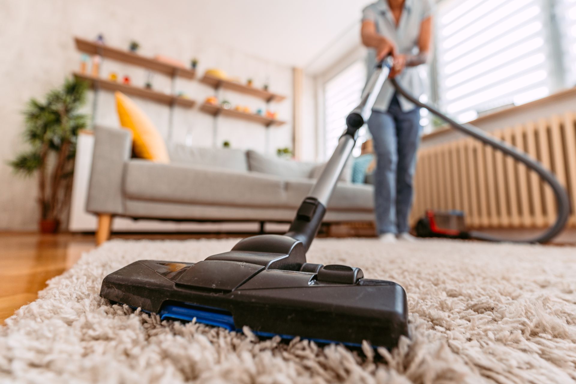 A woman is vacuuming a carpet in a living room.