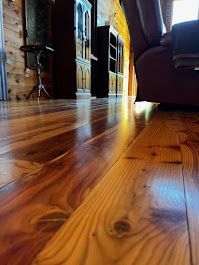 Close-up of polished wooden floor with knots and reflections in a rustic interior.