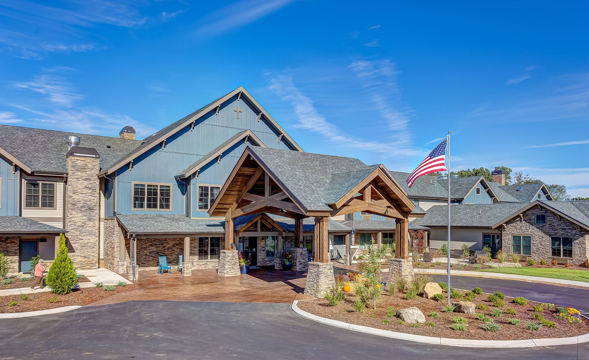 Rustic blue building with stone accents, arched entrance, American flag, blue sky.