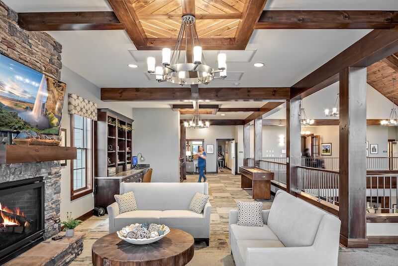 Spacious, rustic-style living room with fireplace, couches, and wood beam ceiling.