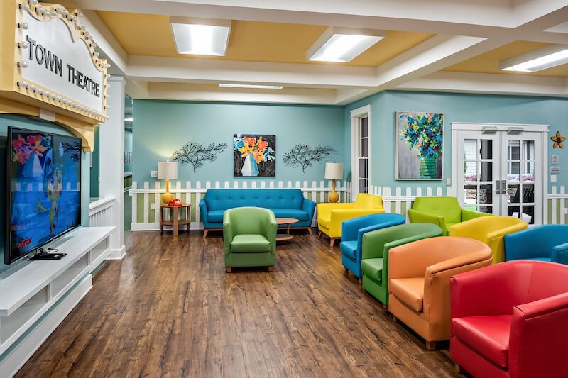 Colorful lounge area with a theater sign and rainbow-colored chairs, inside a building.