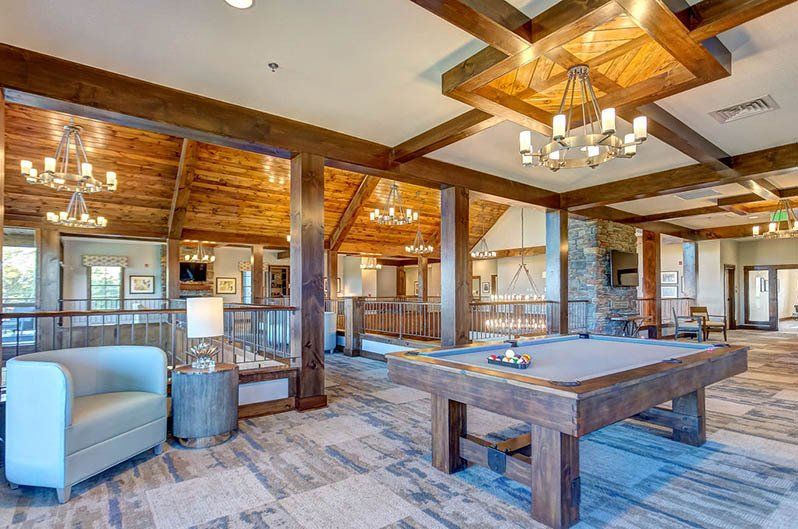 Rustic recreation room with pool table, seating, and chandeliers.