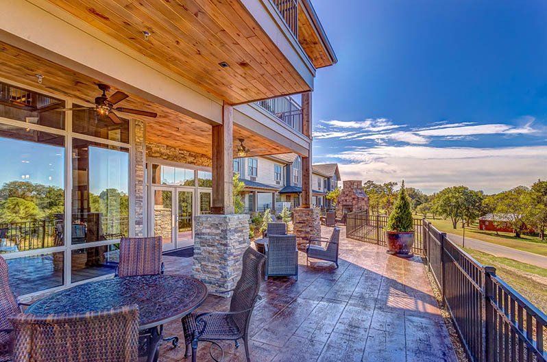 Patio with seating overlooking a landscape, attached to a multi-story building on a sunny day.