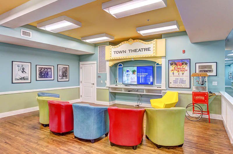 A colorful theater room with stage, seating, popcorn machine, and movie posters.