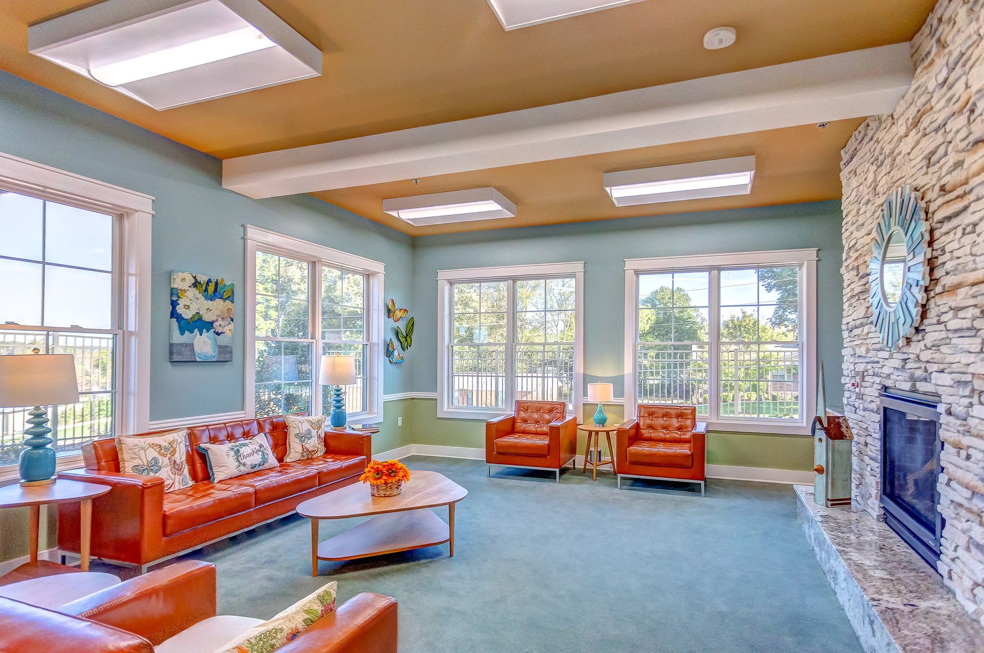 Living room with orange leather furniture, fireplace, and large windows.