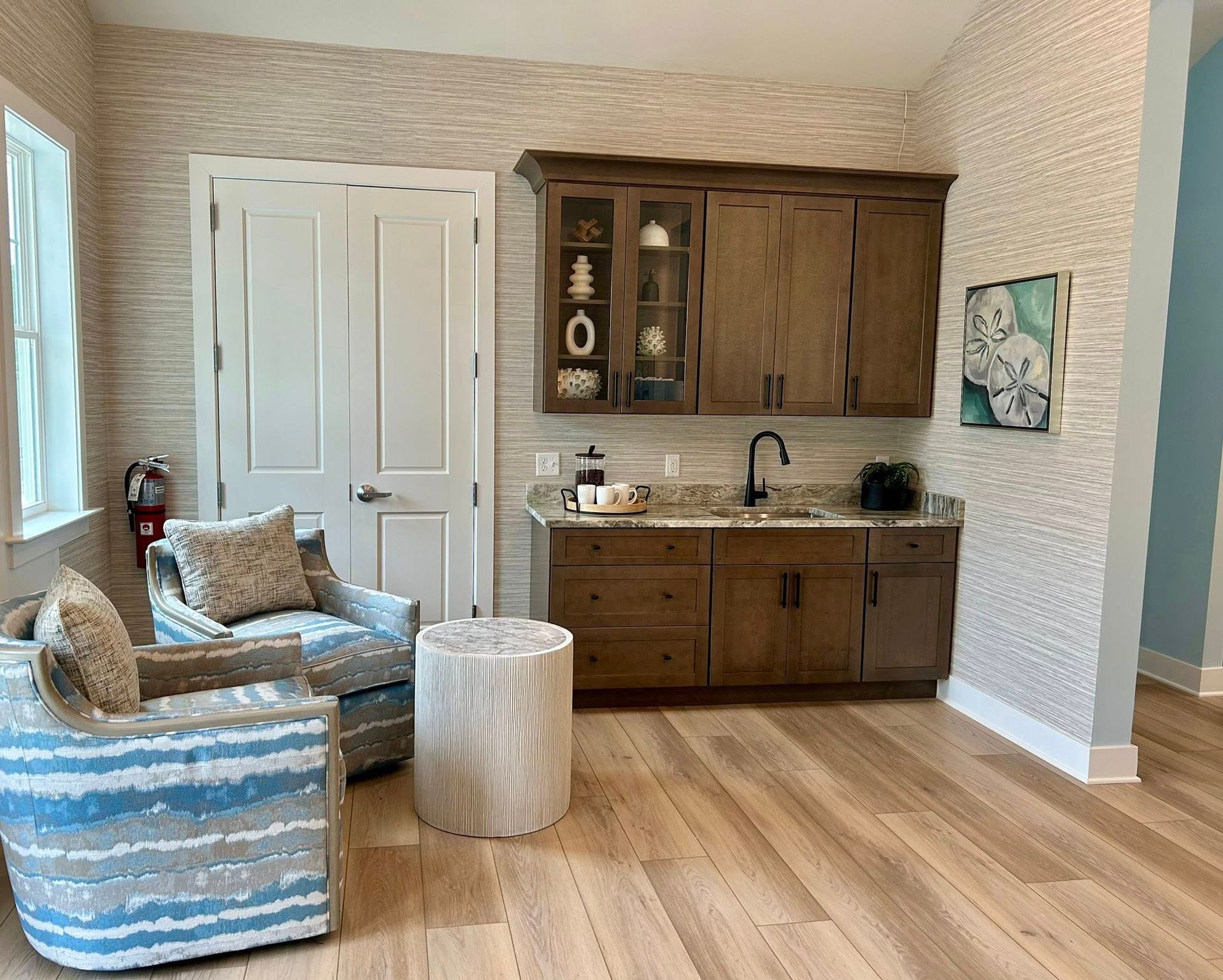 A living room with two chairs , a table , and a sink.