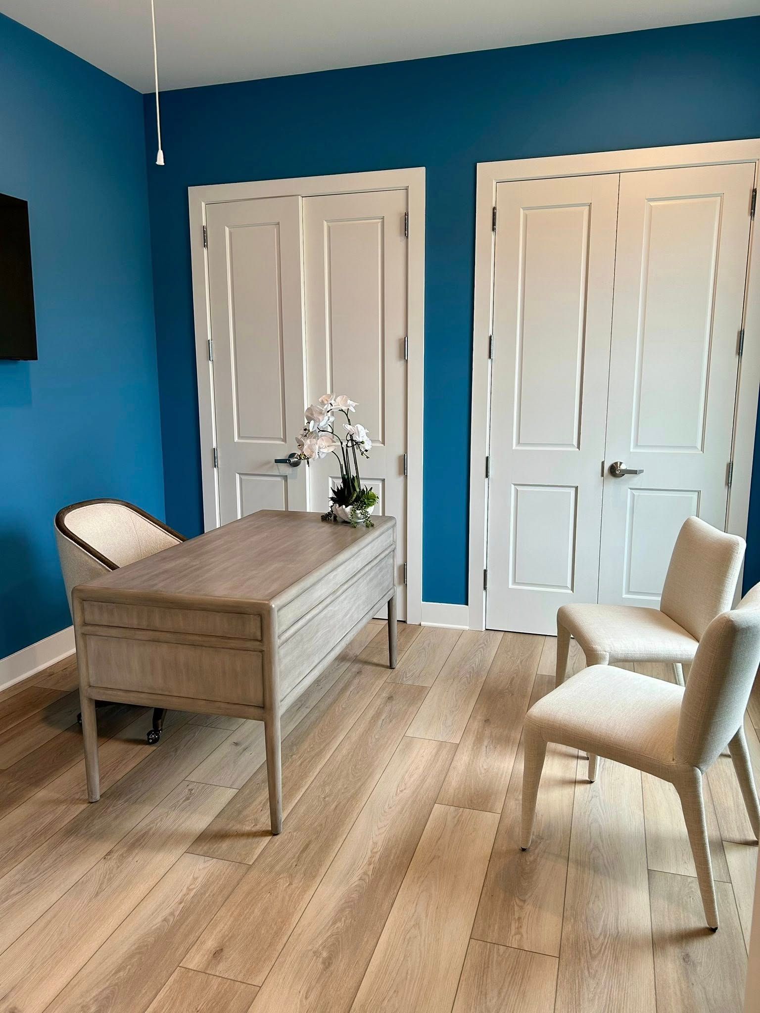 A room with blue walls and a desk and chairs