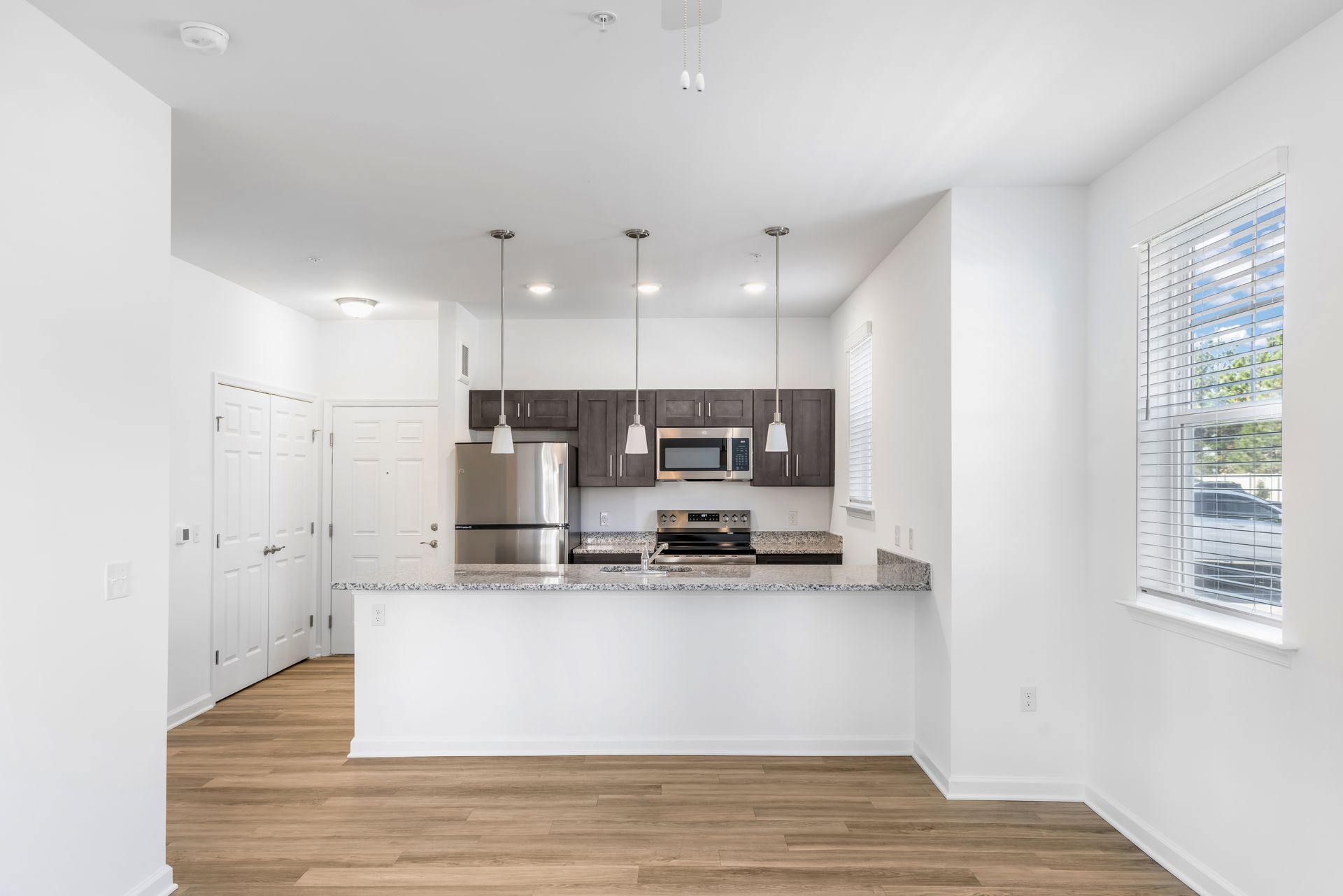 Modern kitchen with dark cabinetry, stainless steel appliances, and a granite countertop island.