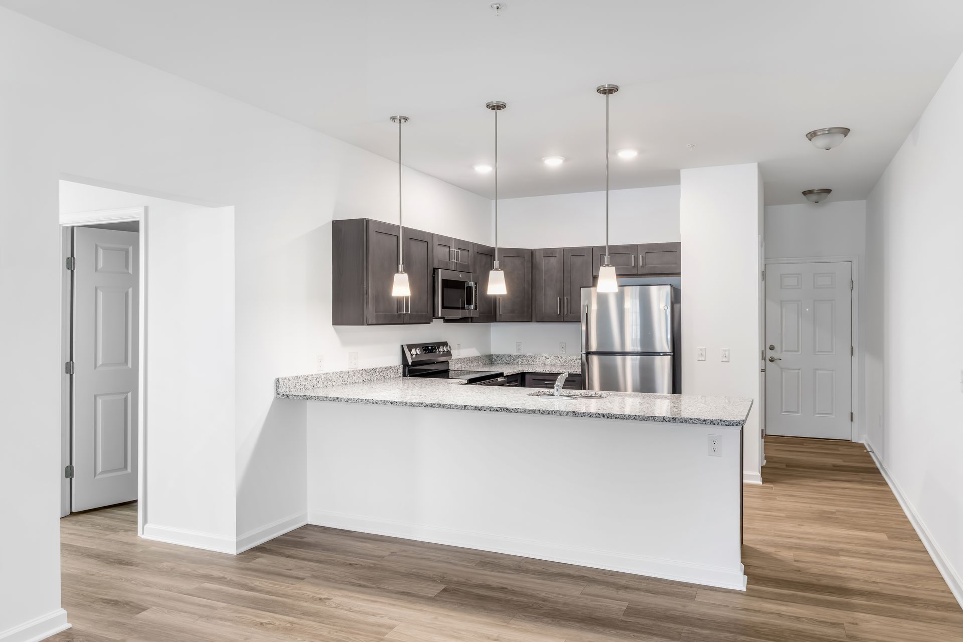 Modern kitchen with gray cabinets, stainless steel appliances, and a granite countertop.