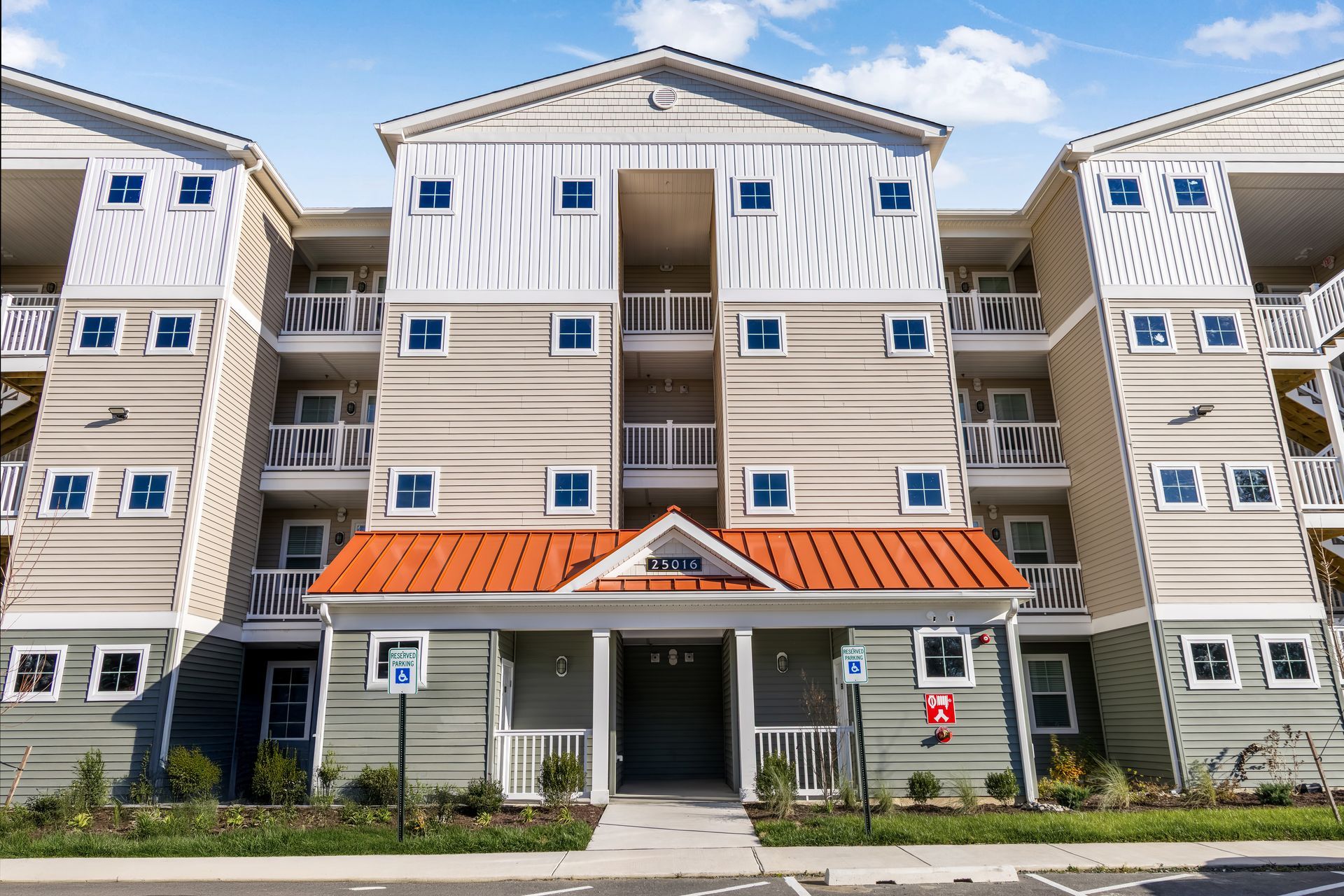 Multi-story apartment building with balconies, orange roof, and blue square windows.
