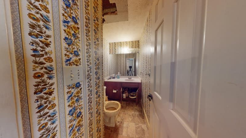 Water-damaged bathroom with peeling wallpaper