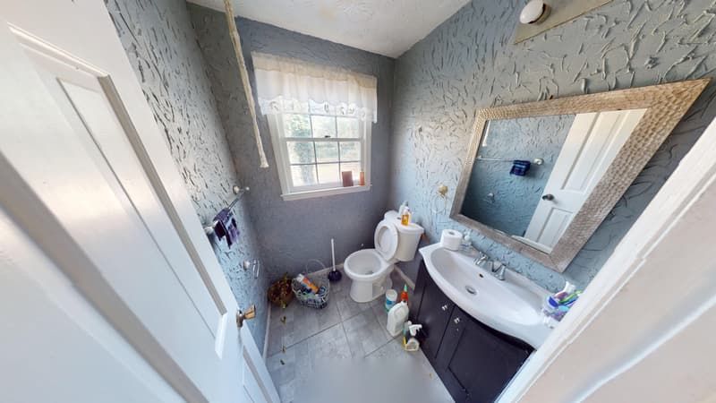 Bathroom before fire damage restoration showing smoke-affected walls and outdated dark vanity
