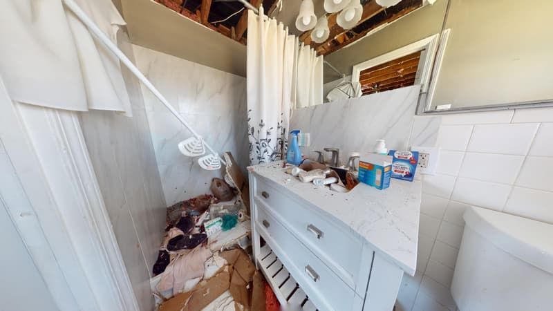 Second bathroom before fire restoration with smoke-stained walls ceiling and tile work